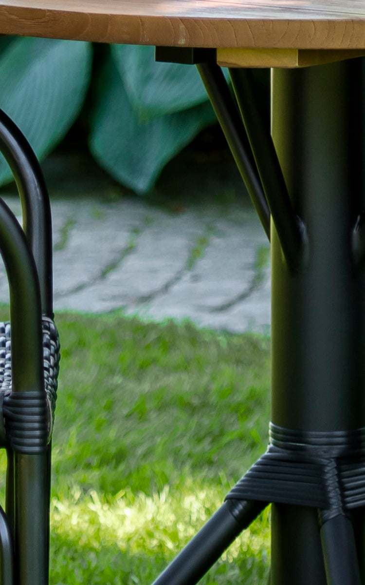 This is a close-up image of Nicole Cafe Table in black aluminium frame black ArtFibre. Detail of the teak top and wrapped base.