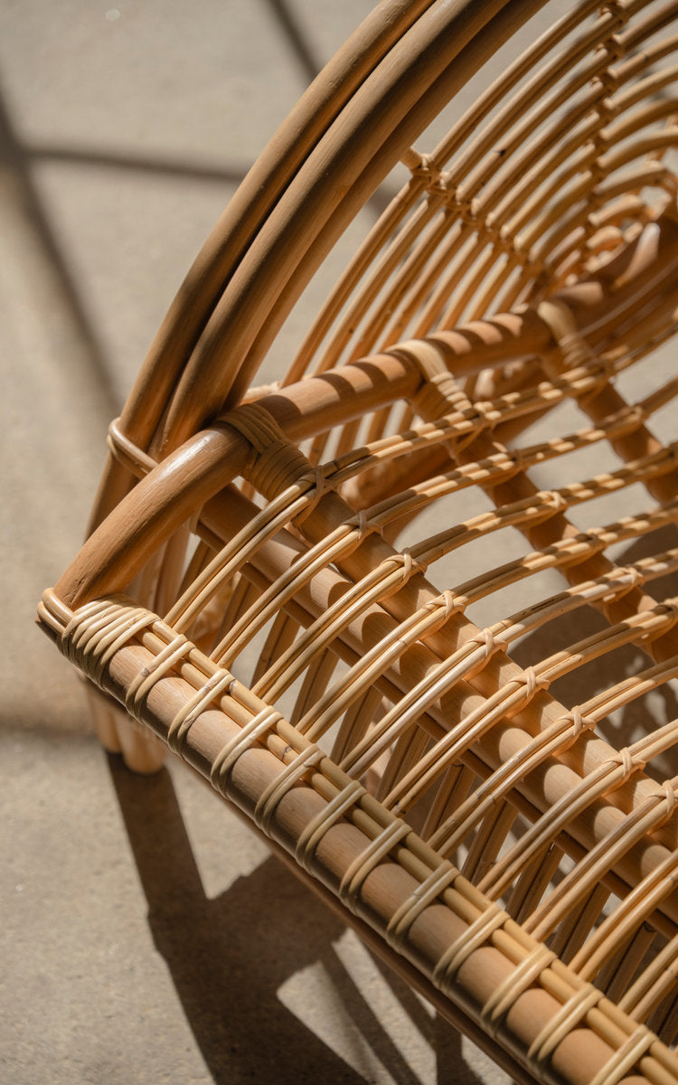 This is a close-up image of Paris Lounge Chair in polished natural rattan. Rattan seat frame and wrapped details in sunlight.