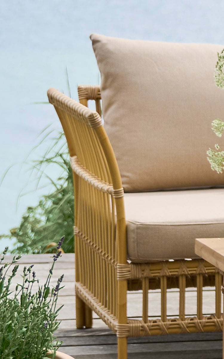This is a close-up image of Maggie Sofa Corner Module in natural aluminium artfibre. Vertical slat frame with wrapped joints and beige cushion.