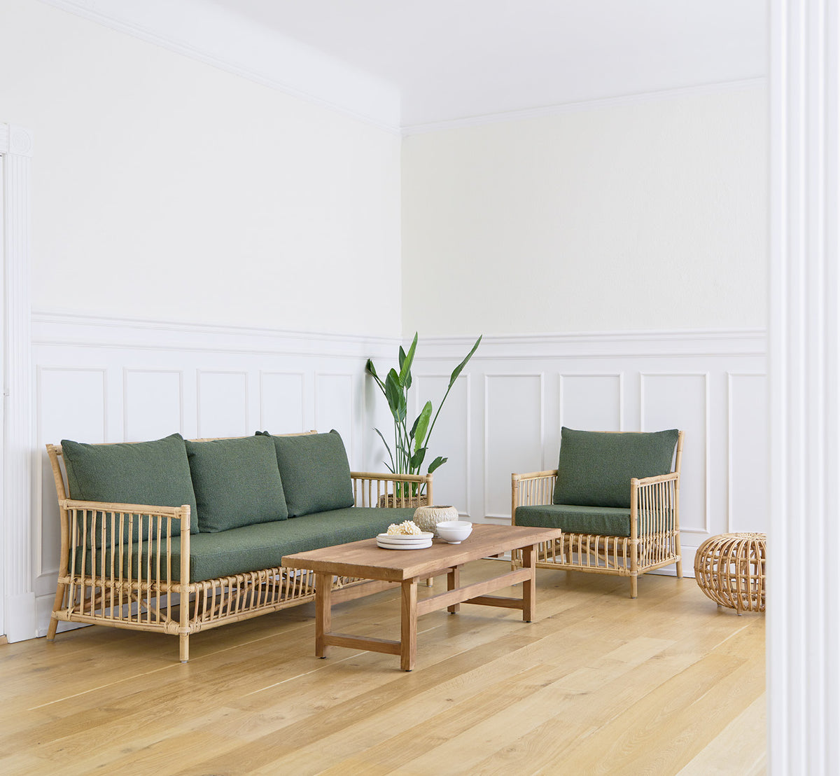 This is a lifestyle image of Caroline Lounge Chair in natural rattan, in a bright Scandinavian living room with herringbone parquet flooring.