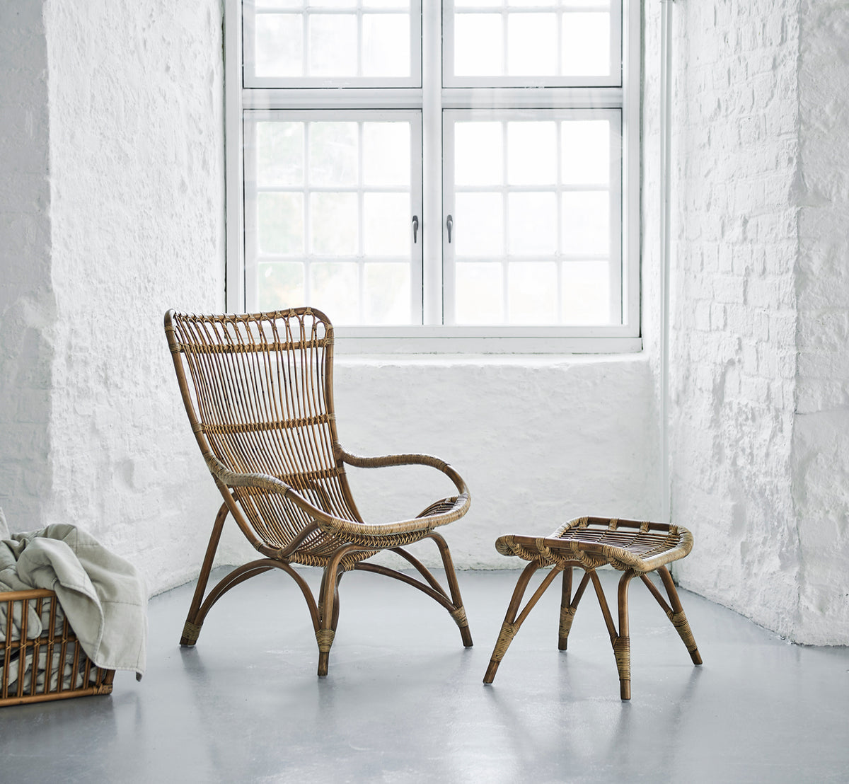 This is a lifestyle image of Monet Lounge Chair in antique rattan. In a butterfly wallpaper room with decorative Moroccan lanterns.