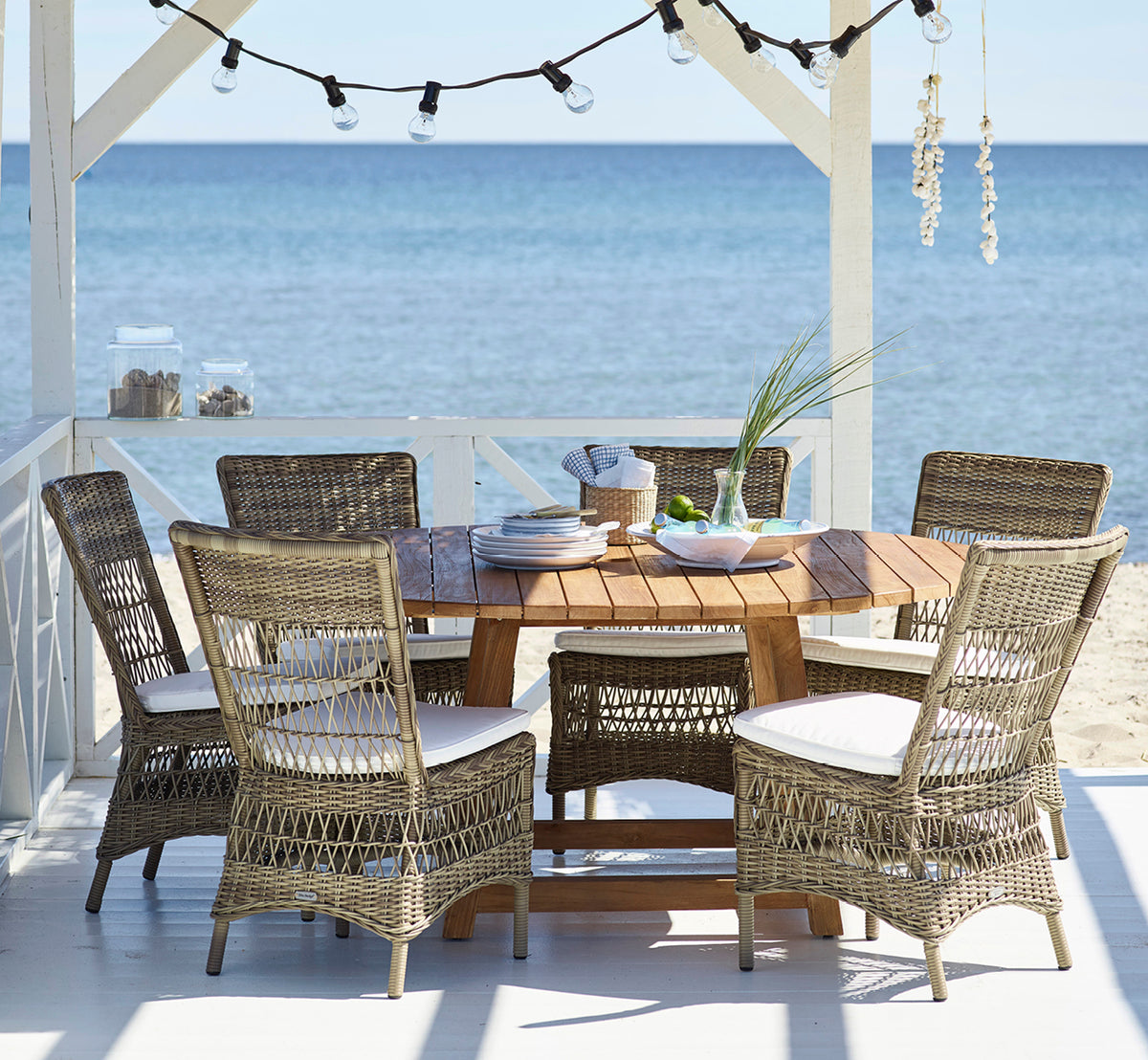 This is a lifestyle image of Marie Exterior Side Chair in antique grey artfibre aluminium. On a beach pavilion set for dinner.