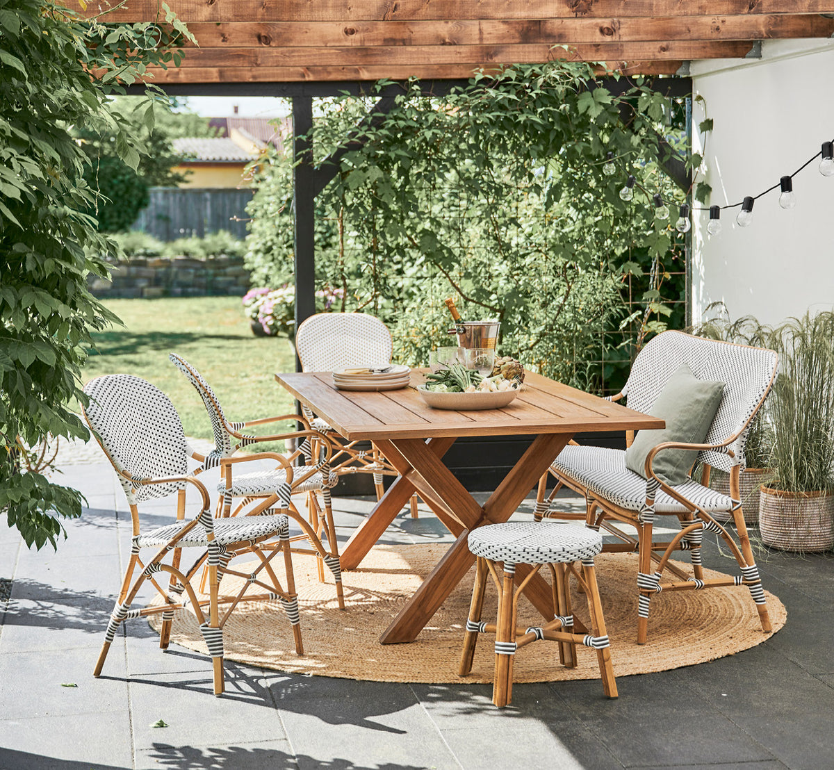 This is a lifestyle image of Colonial Table 160 in outdoor Teak, on a beachside terrace with white wooden decking and sea views.
