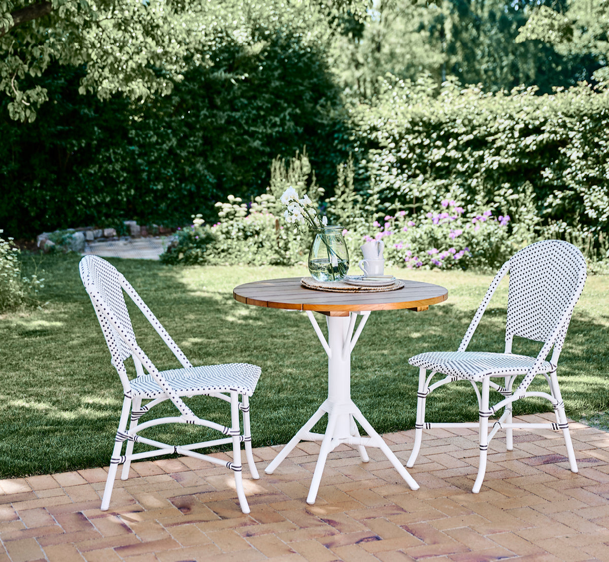 This is a lifestyle image of Nicole Cafe Table in white aluminium frame white ArtFibre. On a beach pavilion with Piano armchairs.