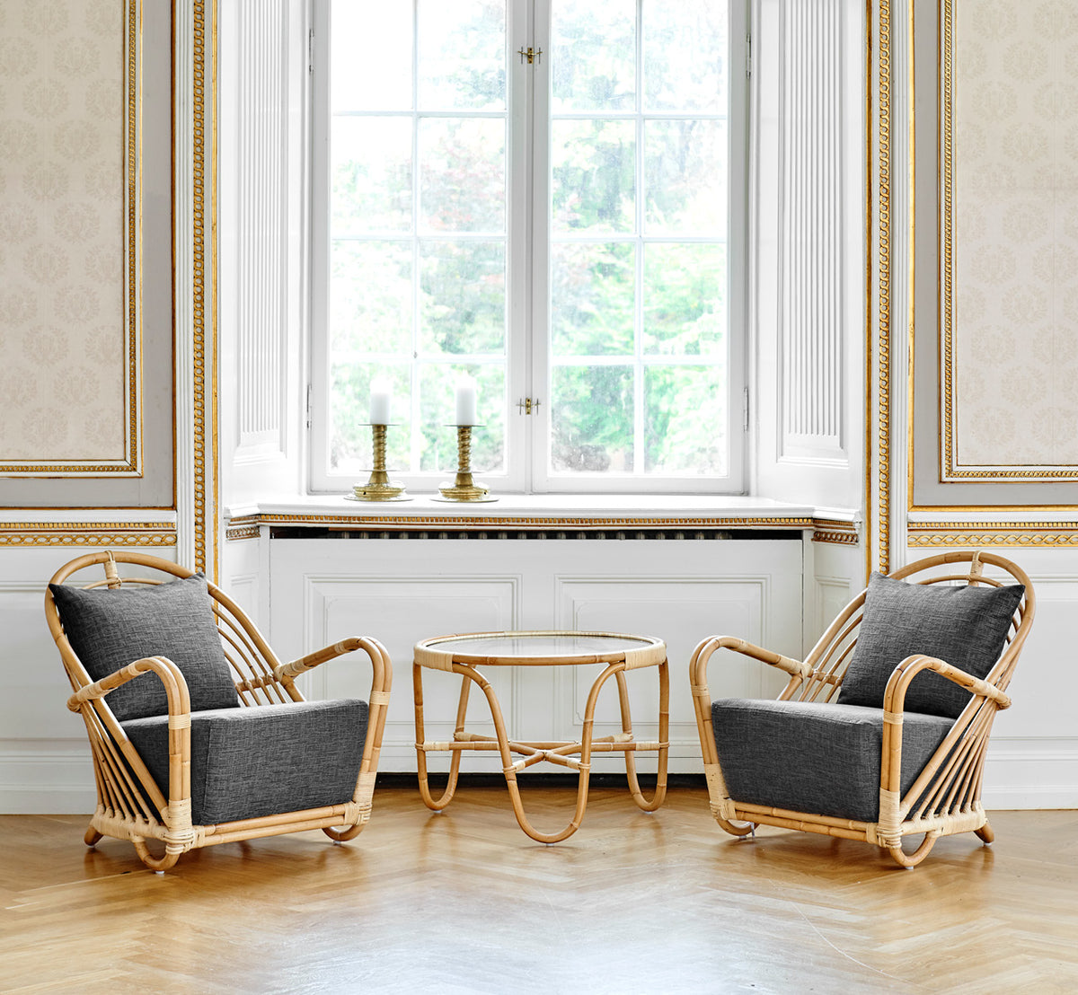 This is a lifestyle image of Charlottenborg Coffee Table in polished Natural Rattan, in an elegant classical interior with ornate golden mouldings.