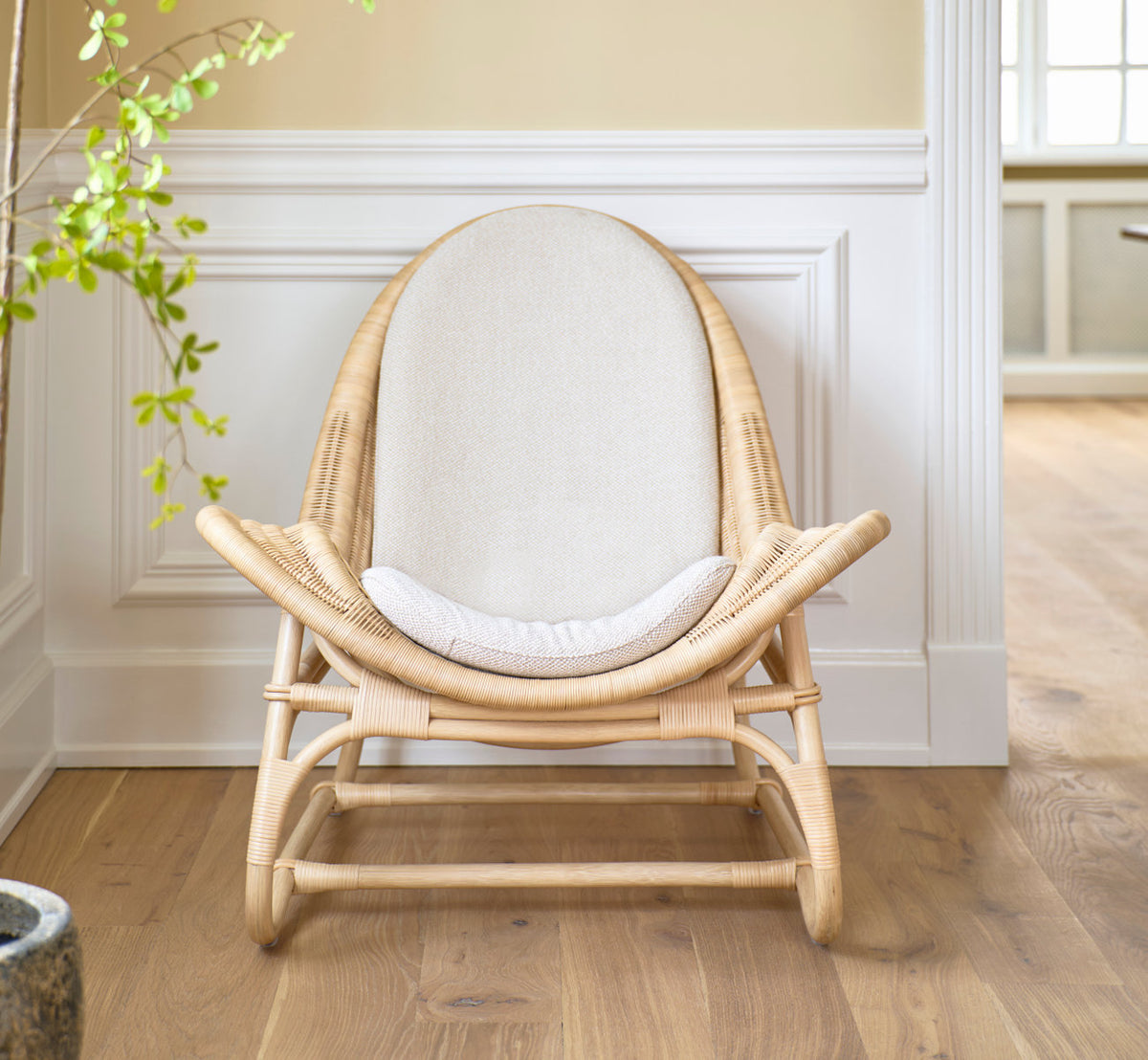 This is a lifestyle image of Pacifique Lounge Chair in natural core weave rattan frame. With linen cushion by white panels.