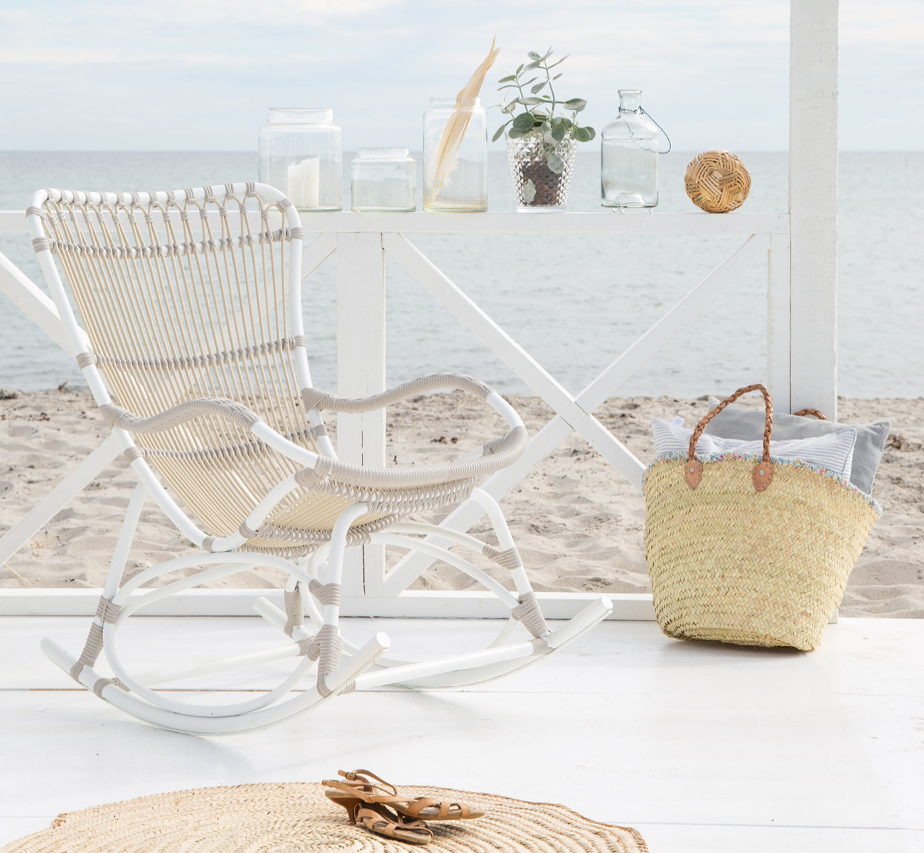 This is a lifestyle image of Monet Exterior Rocking Chair in dove white aluminium artfibre. On a beach pavilion with ocean view.