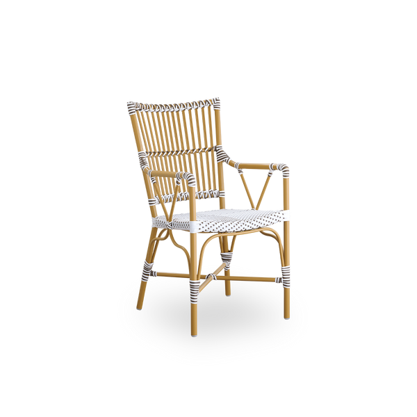 Side view of Monique outdoor dining armchair. Aluminium frame in almond color with seat woven with ArtFibre in white with brown dots. Inspired by 1950s bistro design.