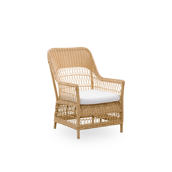 Side view of the Dawn outdoor lounge chair in natural color, inspired by British colonial style. Romantic lounge chair with armrest and a high backrest. Fully woven ArtFibre on hand-bent aluminum frame.
