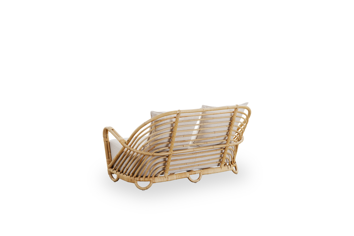 Back side view of the Charlottenborg 2-seater sofa in polished natural rattan, designed by Arne Jacobsen. The sofa features a curved back and armrests integrated into the base, handcrafted from high-quality Indonesian rattan.