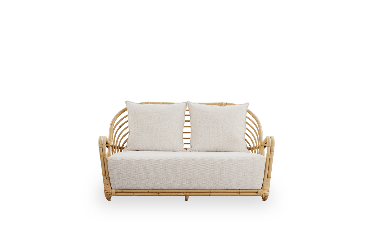 Front view of the Charlottenborg 2-seater sofa in polished natural rattan, designed by Arne Jacobsen. The sofa features a curved back and armrests integrated into the base, handcrafted from high-quality Indonesian rattan.