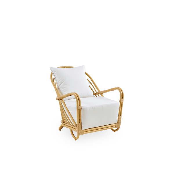 Side view of the Charlottenborg Exterior lounge chair in rattan look, designed by Arne Jacobsen. The chair features a curved back and armrests integrated into the base, handcrafted with an Alu-Rattan frame and woven ArtFibre details.