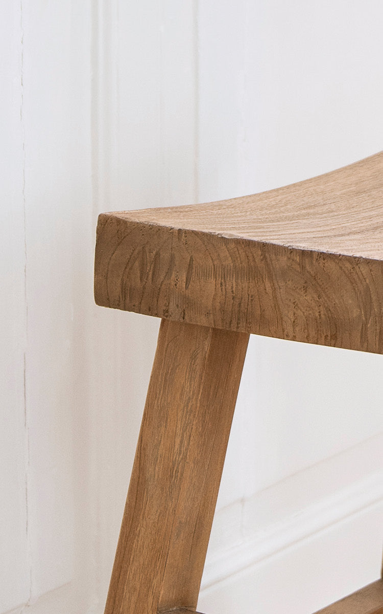 This is a close-up image of Charles Stool in teak indoor.
