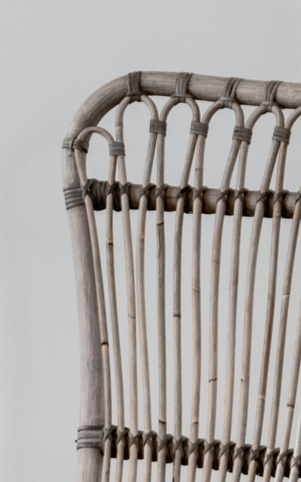 This is a close-up image of Monet Lounge Chair in taupe rattan. Detail of the looped arch design and vertical rods in warm taupe tone.