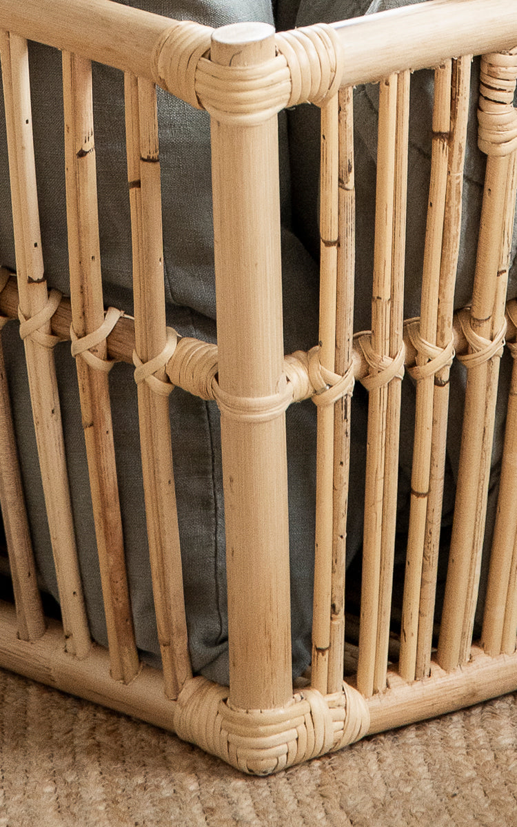 This is a close-up image of Marche Basket in natural rattan. Vertical rattan poles with wrapped joints and open slat construction.