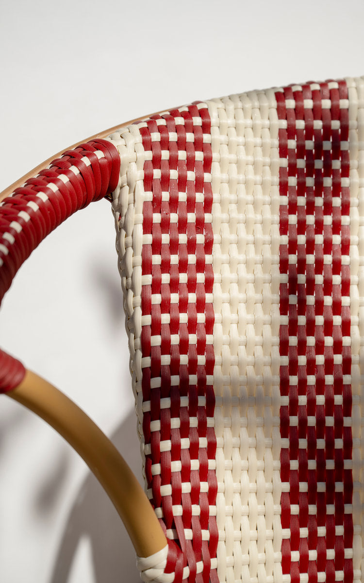 This is a close-up image of Madeleine Exterior Bench in almond aluminum frame striped ivory burgundy. Striped weave and wrapped armrest in daylight.
