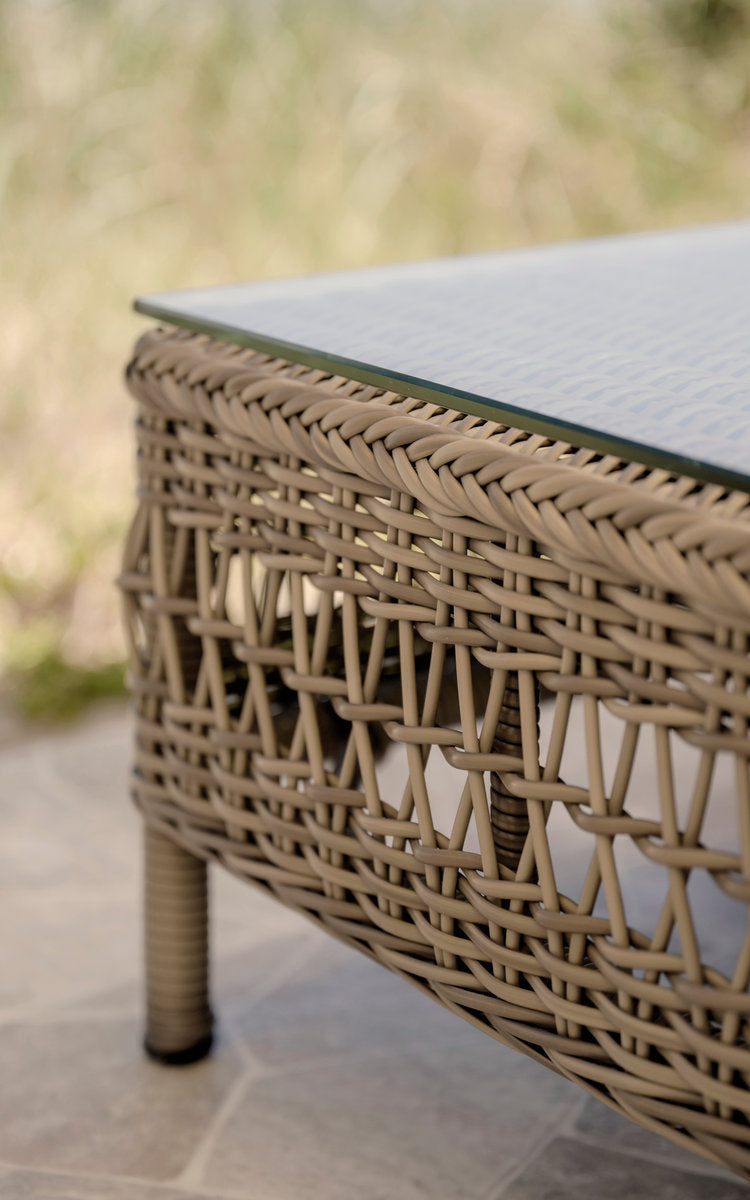 This is a close-up image of Mona Exterior Modular Sofa-Pouf Module w. Glass in antique grey artfibre aluminium. Open weave beneath a glass top.