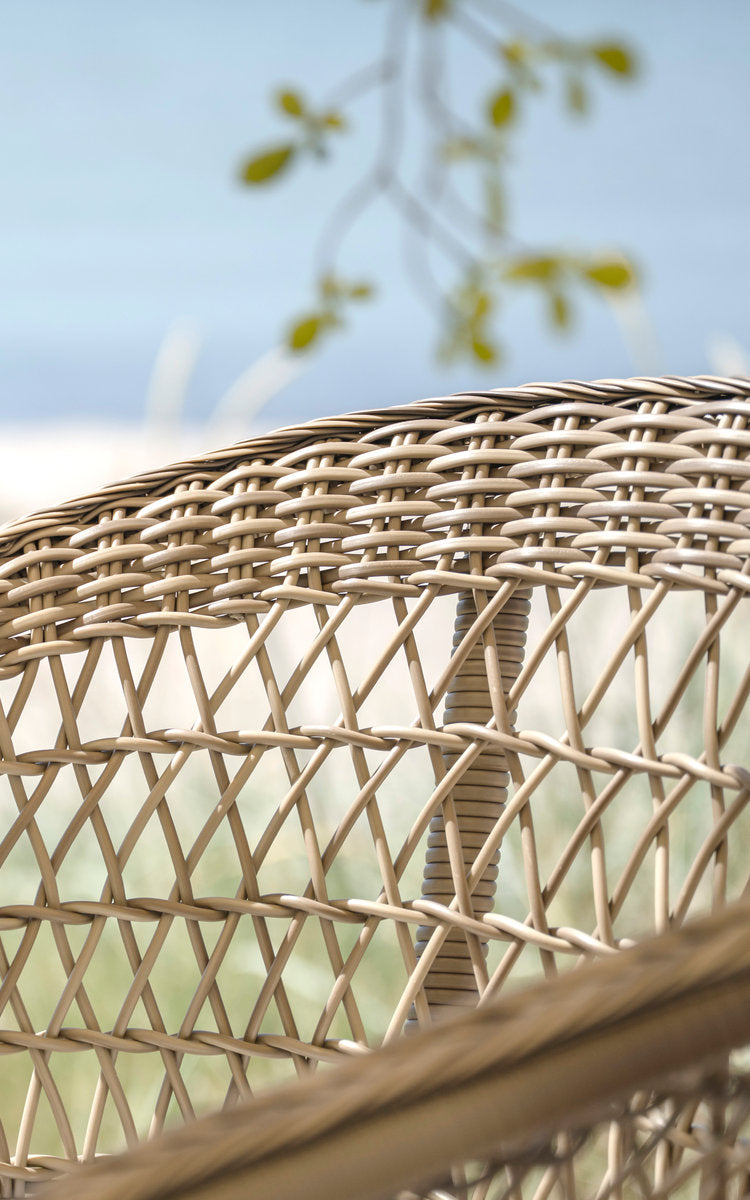 This is a close-up image of Emma Exterior Barstool in antique grey artfibre aluminium. Open diamond weave backrest by the sea.