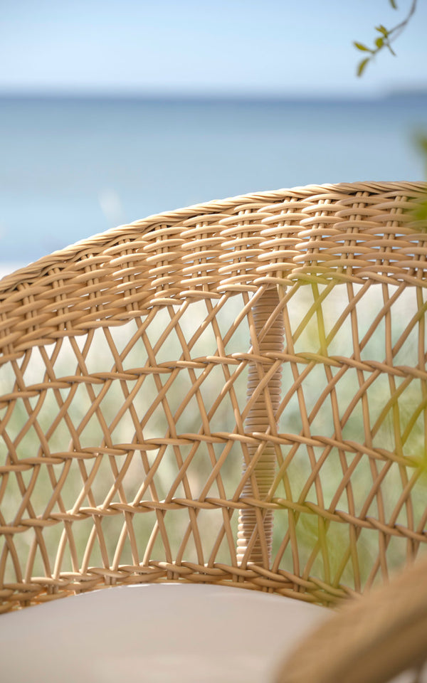 This is a close-up image of Emma Exterior Barstool in natural artfibre aluminium. Open weave backrest with sea view.