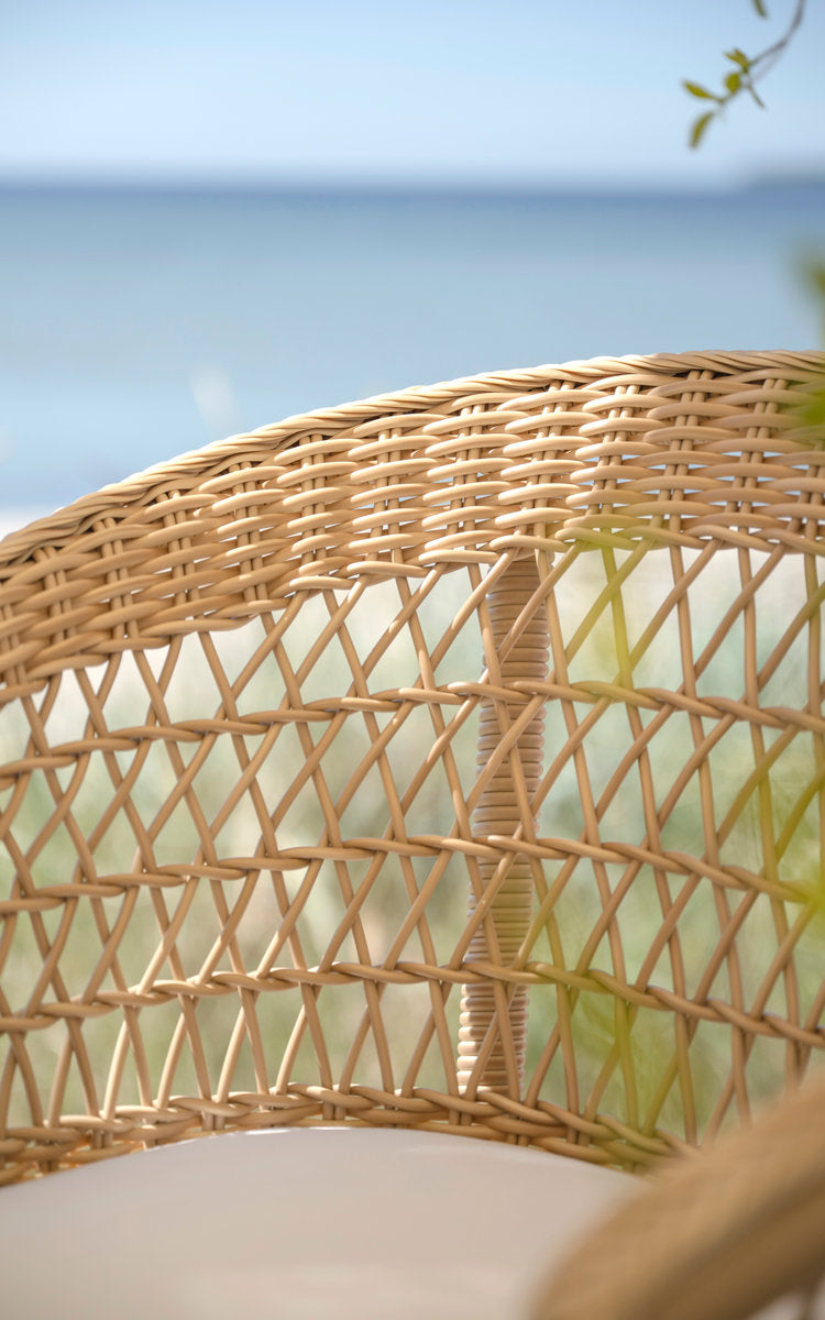 This is a close-up image of Emma Exterior Barstool in natural artfibre aluminium. Open weave backrest with sea view.