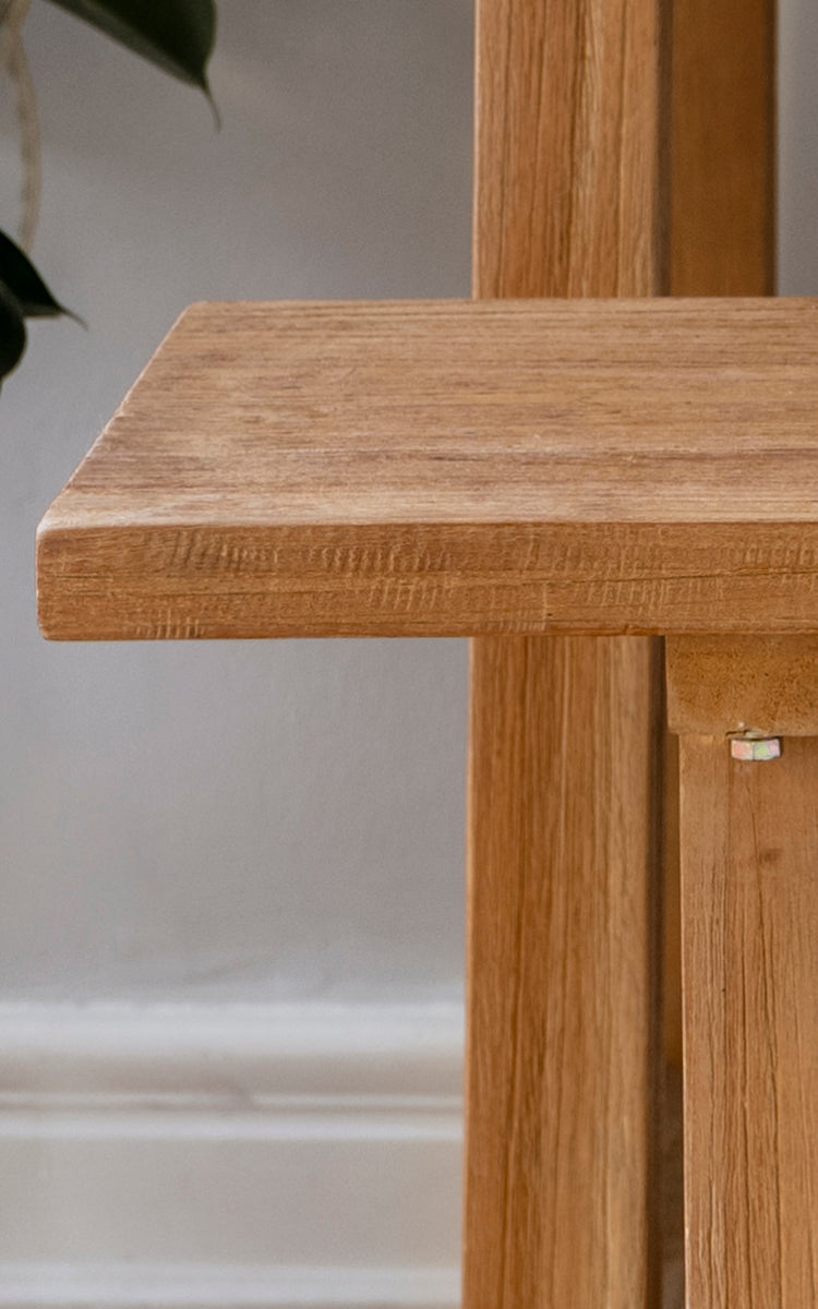 This is a close-up image of Lucas Teak Bench in teak indoor. The solid teak surface shows warm wood grain with clean edges and sturdy joinery.