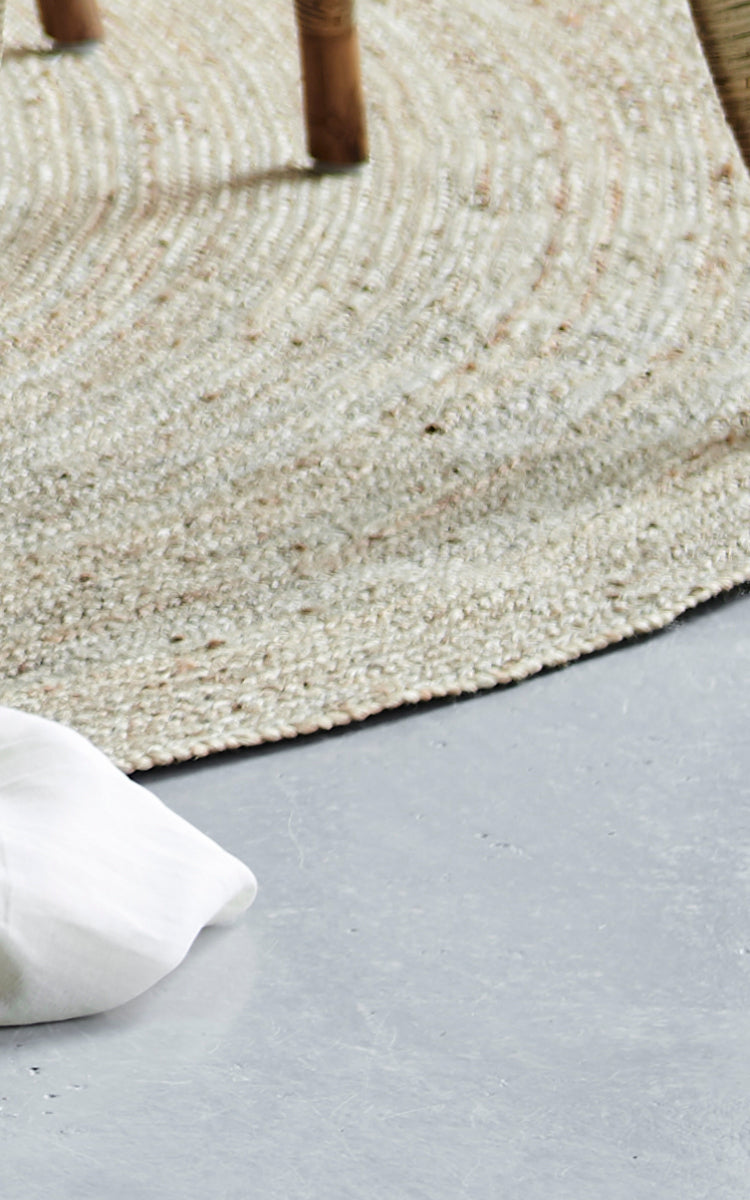 This is a close-up image of Jute Carpet Ø280 in grey jute. The tightly woven texture and rounded edge are shown on a concrete floor.