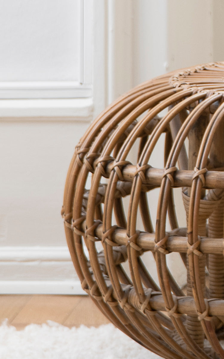 This is a close-up image of Ottoman Small in polished antique rattan. Detail of the open rattan cage structure with cross-tied bindings.