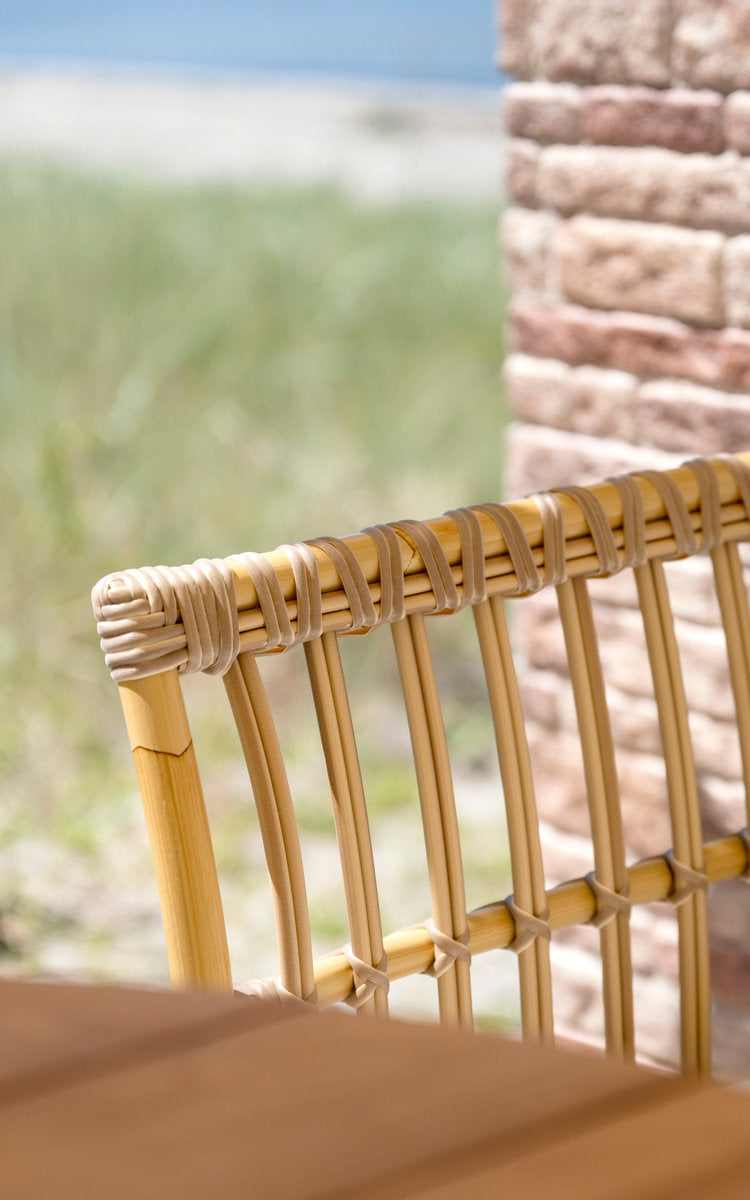 This is a close-up image of Meghan Exterior Dining Bench-Center Module in natural aluminium artfibre. Bound slatted backrest by a brick wall.