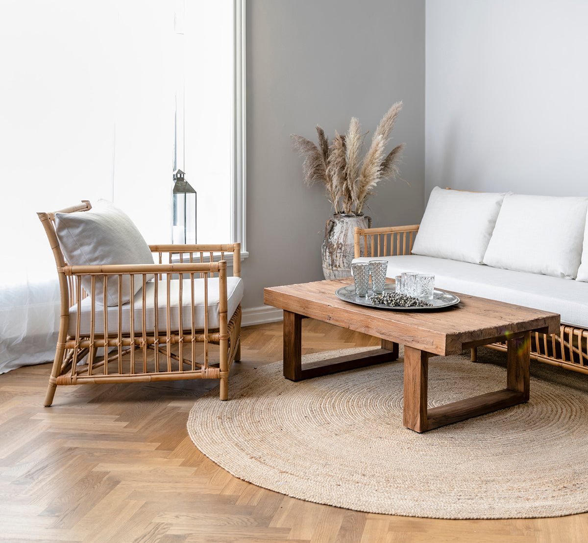 This is a lifestyle image of Caroline Lounge Chair in natural rattan, in a bright Scandinavian living room with herringbone parquet flooring.