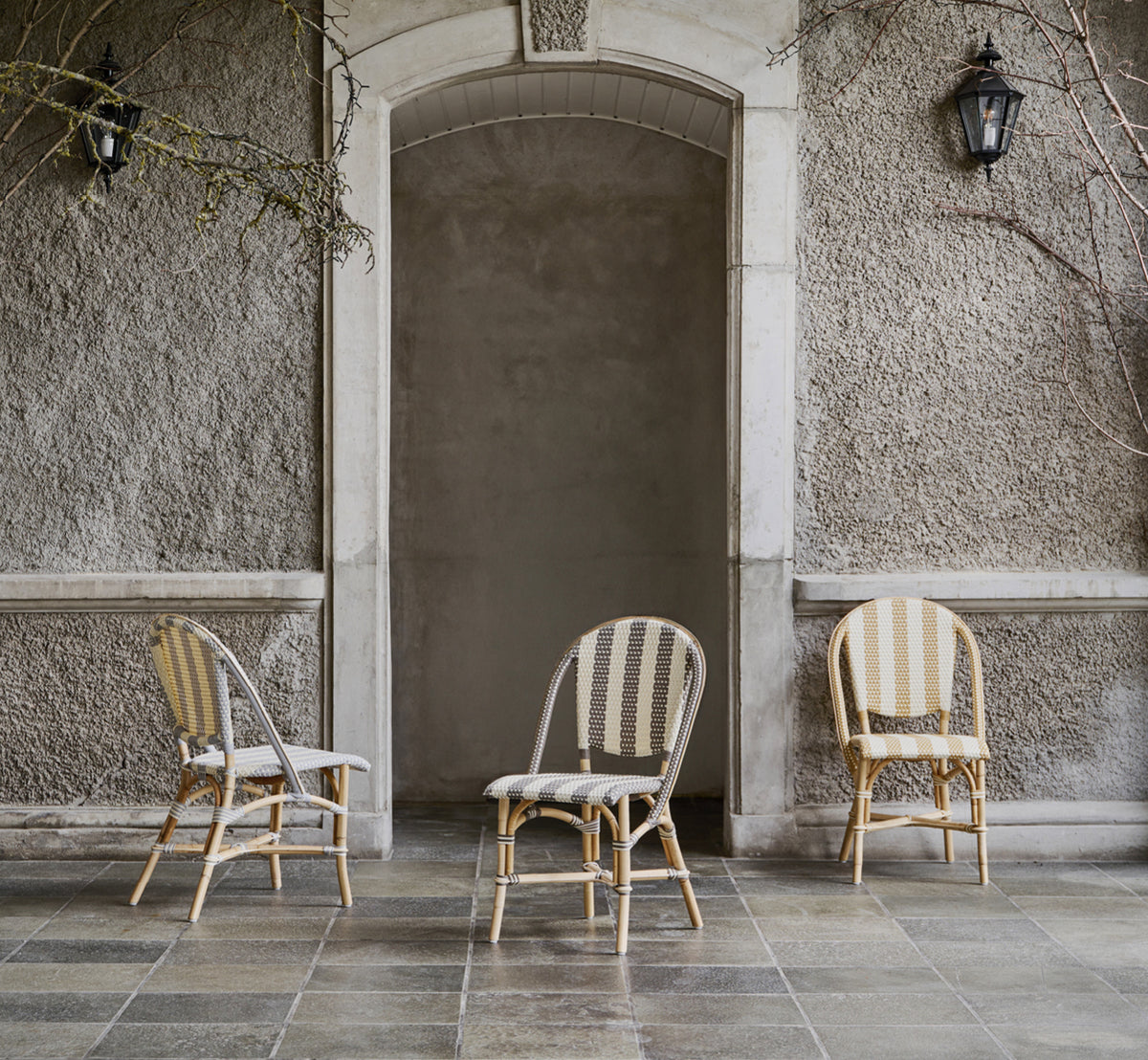This is a lifestyle image of Sofie Dining Chair in striped cappuccino ivory artfibre skin on natual rattan frame. Styled in a bright interior setting.
