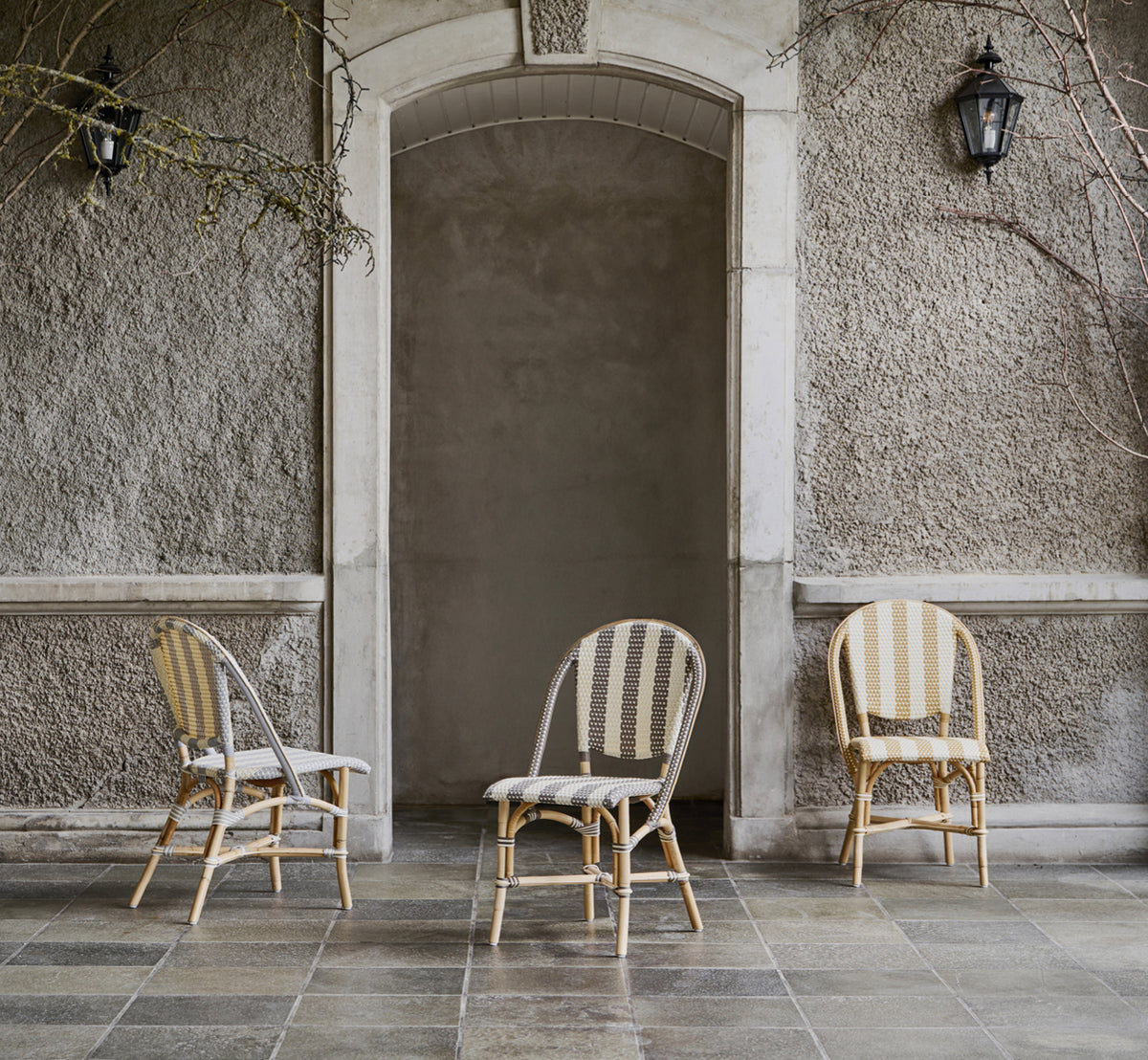 This is a lifestyle image of Sofie Dining Chair in striped grey ivory artfibre skin on natual rattan frame. Styled in a bright interior setting.