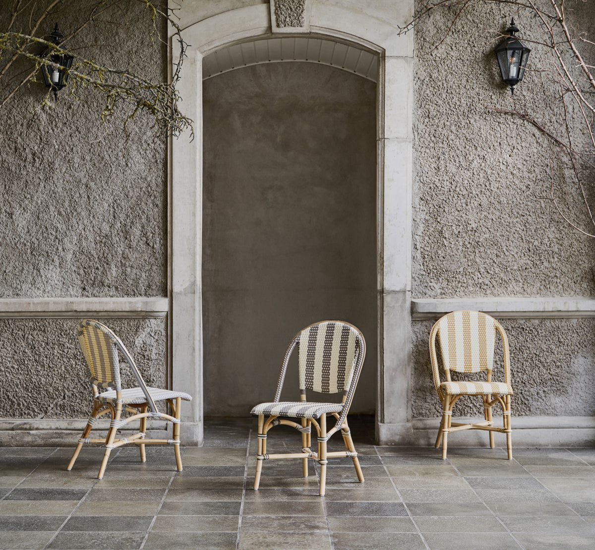 This is a lifestyle image of Sofie Dining Chair in striped honey ivory artfibre skin on rattan frame. Styled in a bright interior setting.