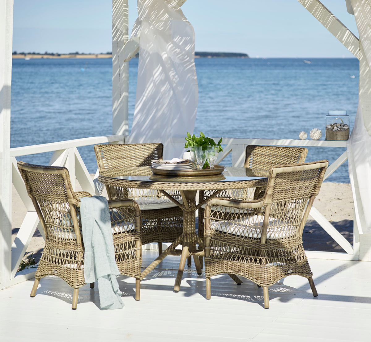 This is a lifestyle image of Grace Exterior Dining Table in antique Grey ArtFibre Aluminium, in a lush garden patio with stone tile flooring and.