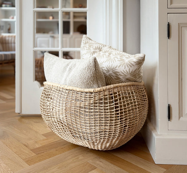 This is a lifestyle image of Folia Basket in natural core weave iron frame, in a bright white interior with wainscoting, styled with dried flowers.