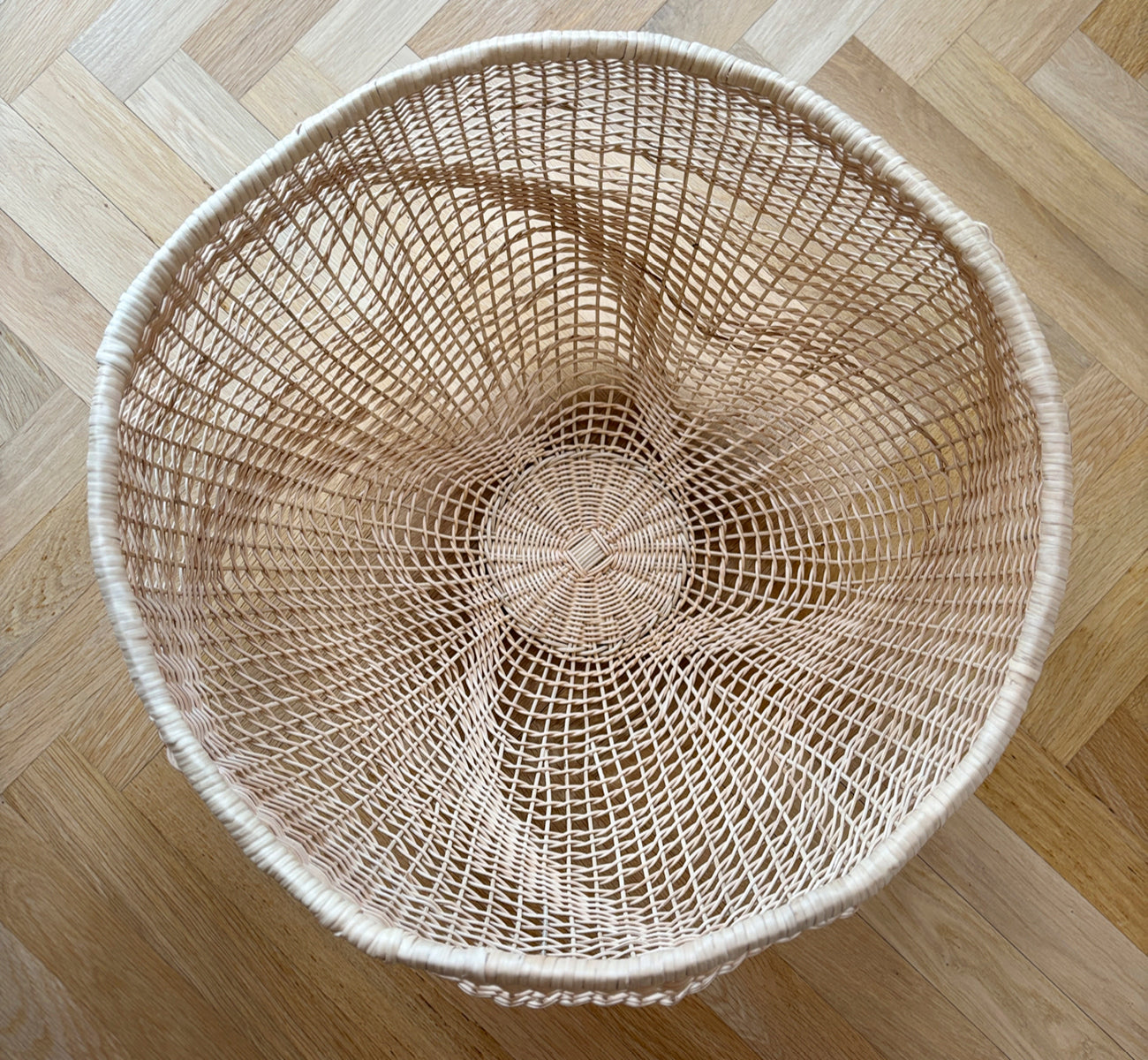 This is a lifestyle image of Folia Basket in natural core weave iron frame, in a bright white interior with wainscoting, styled with dried flowers.