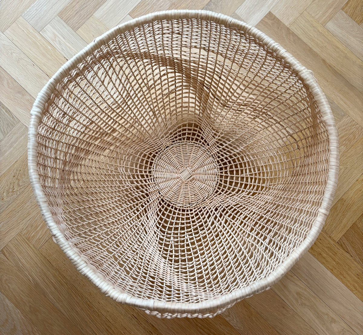 This is a lifestyle image of Folia Basket in natural core weave iron frame, in a bright white interior with wainscoting, styled with dried flowers.