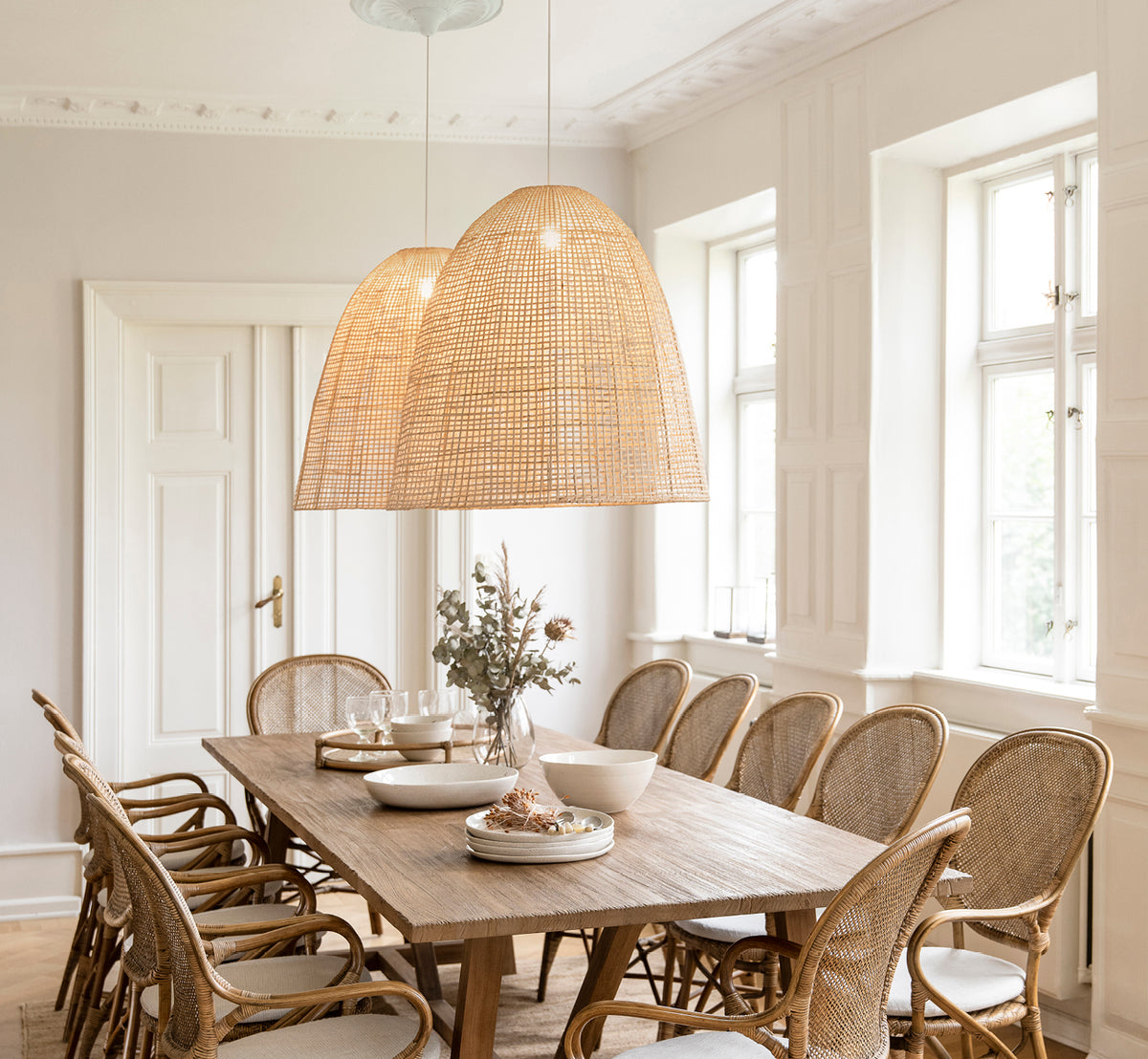 This is a lifestyle image of Showroom Lampshade in natural core weave artfibre & aluminium. Illuminating a dining table with rattan chairs below.