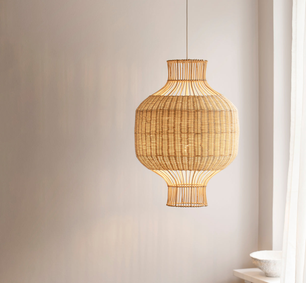 This is a lifestyle image of Hikari Lampshade in natural core weave iron frame, displayed in a bright interior setting.