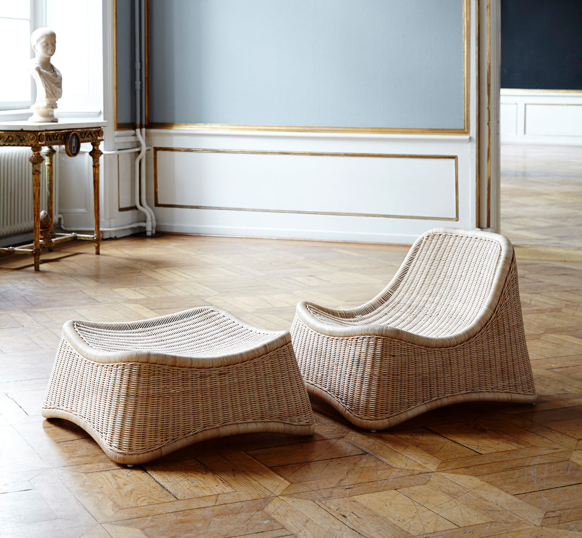 This is a lifestyle image of Chill Lounge Chair in natural core weave Rattan frame, in an elegant classical interior with ornate golden mouldings.
