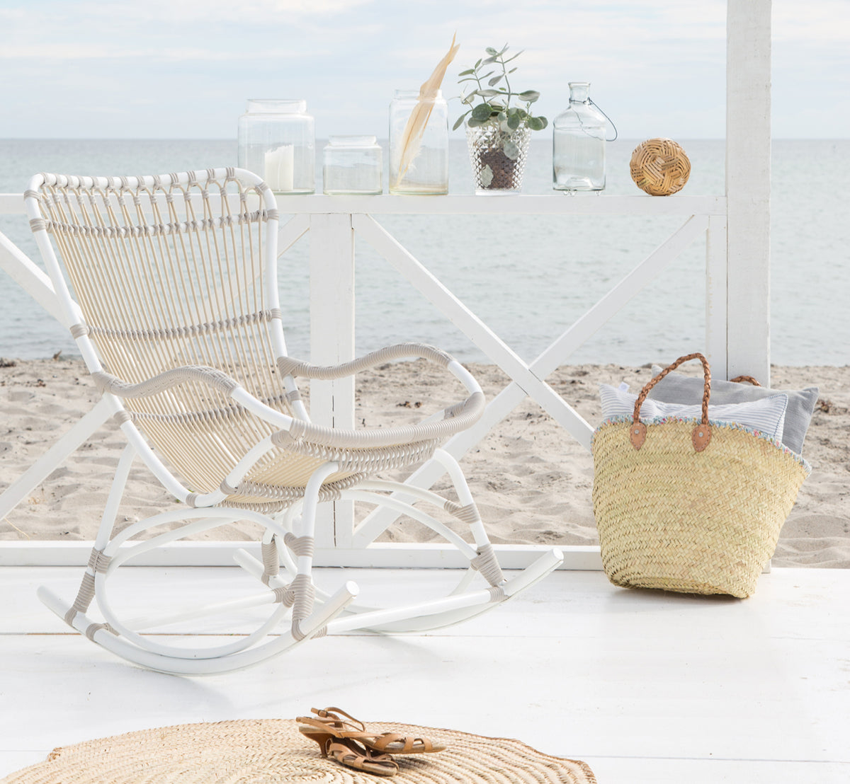 This is a lifestyle image of Monet Exterior Rocking Chair in dove white aluminium artfibre. On a beach pavilion with ocean view.