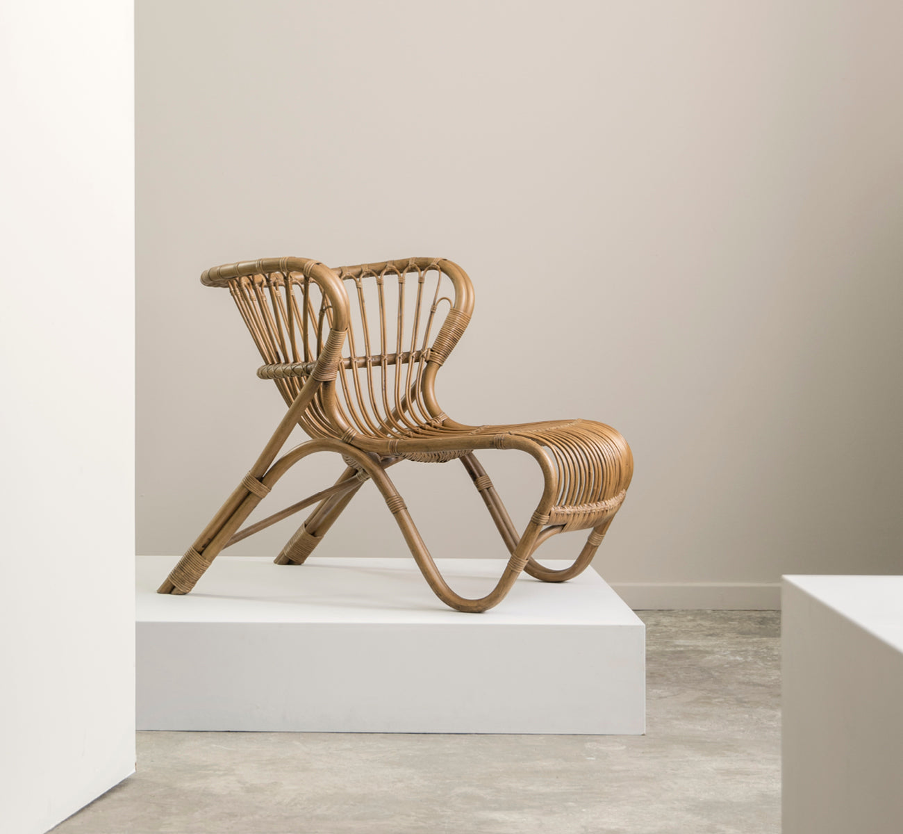 This is a lifestyle image of Fox Lounge Chair in polished Antique Rattan, in a warm interior with ochre wainscoting and dark herringbone parquet.
