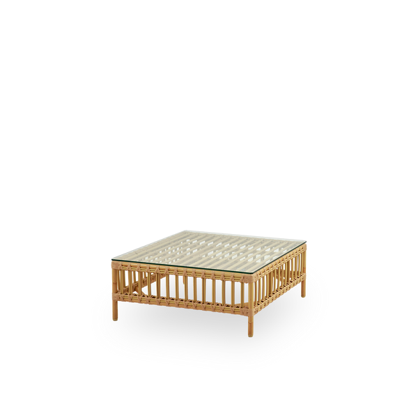 Side view of Maggie outdoor sofa pouf module in Natural color presented with glass top to be used as side table. Aluminium frame with handpainted rattan look with ArtFibre windings.